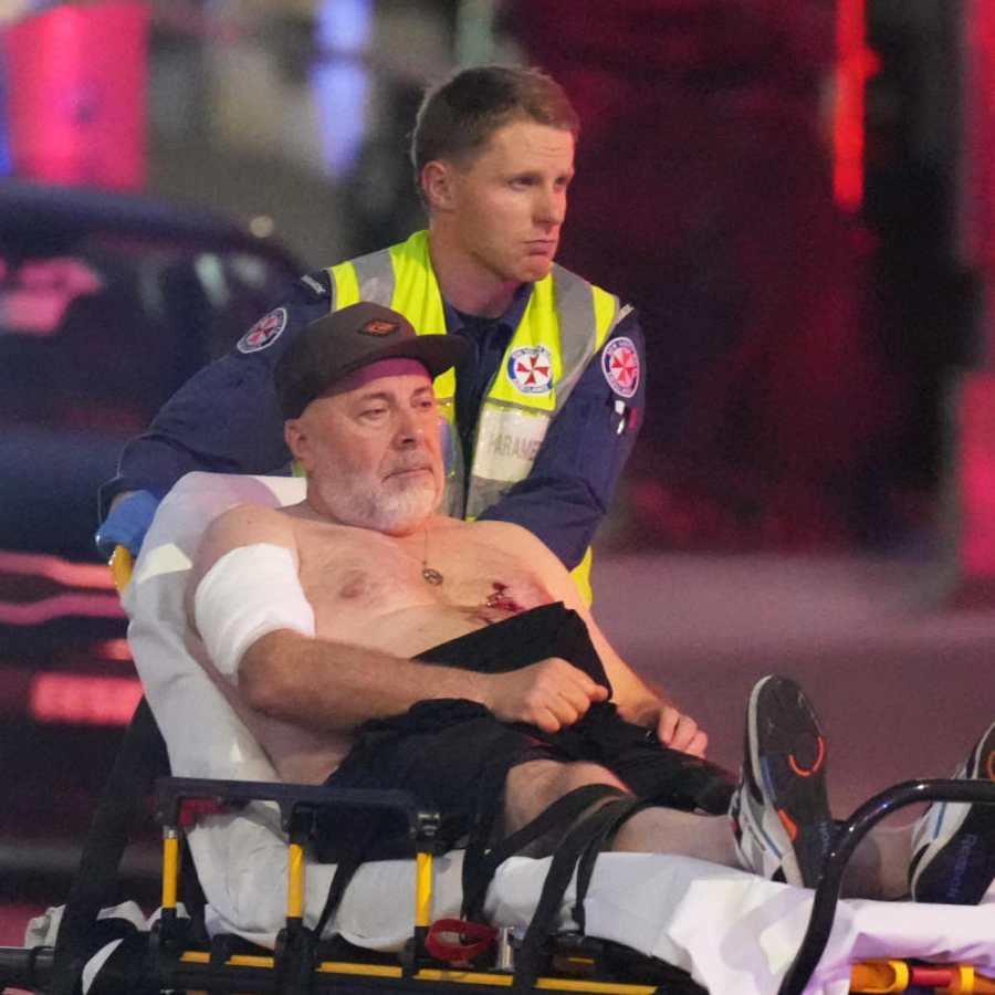 সিডনির বন্ডাই সৈকতে হামলার পরে আহতকে উদ্ধার করে নিয়ে যাচ্ছে পুলিশ।