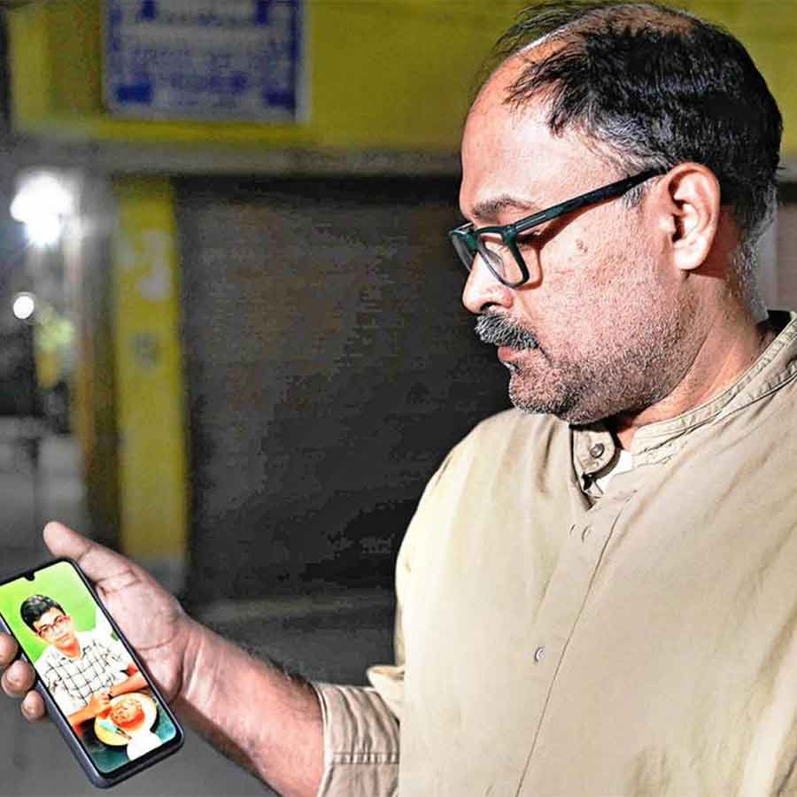 ছেলে অরণ্যর জন্মদিন পালনের ছবি মোবাইলে দেখছেন বাবা সমীরণ চক্রবর্তী।