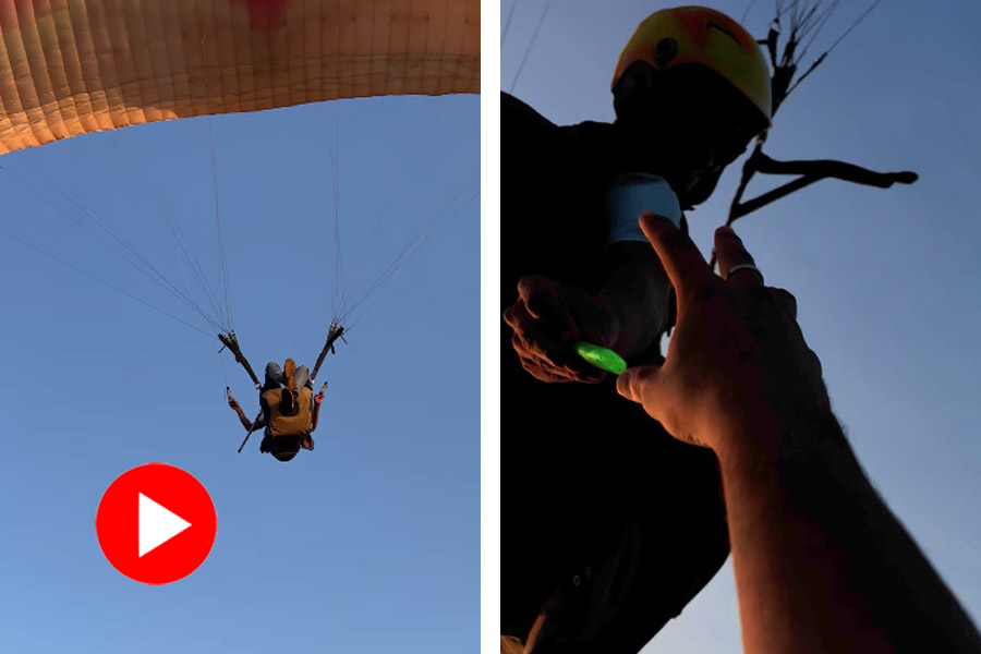 Paraglider helps young tourists by giving them lighter while hanging in sky