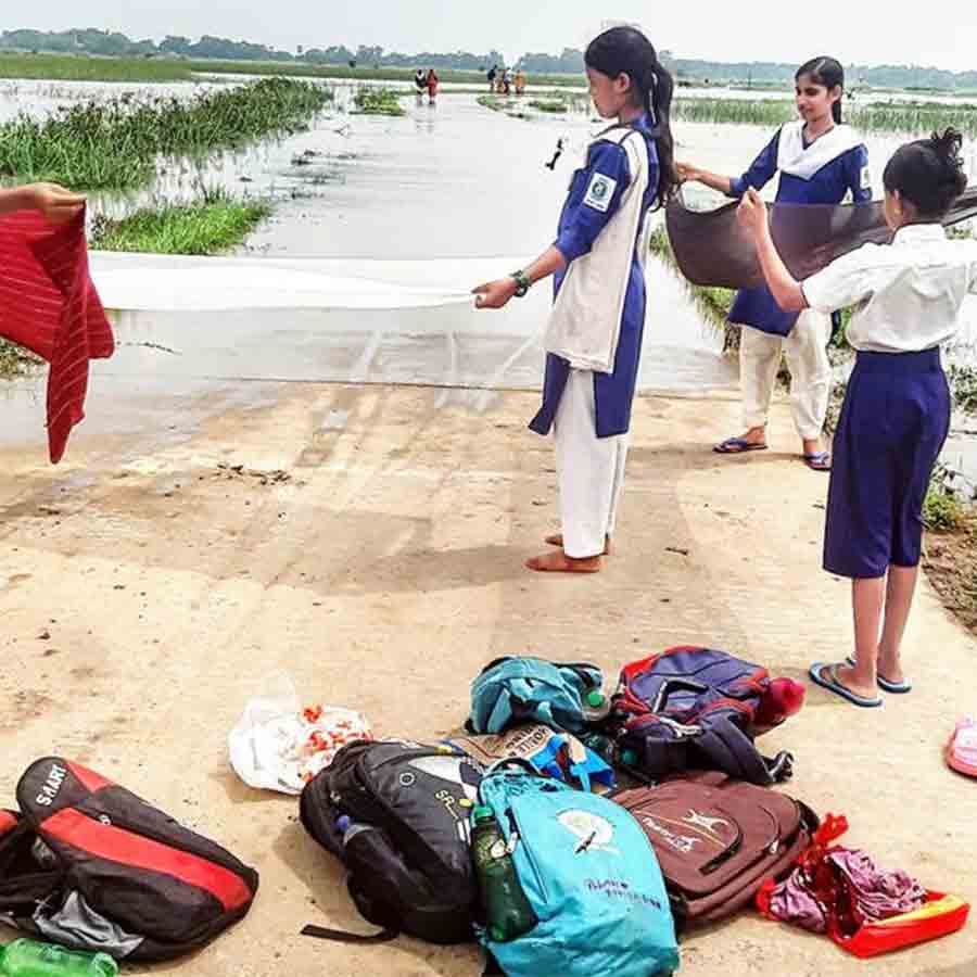 জল পেরিয়ে এসে পোশাক শুকিয়ে নিচ্ছে ছাত্রীরা। শুক্রবার লাভপুরের জয়চন্দ্রপুর থেকে ধ্রুববাটি রাস্তায়।