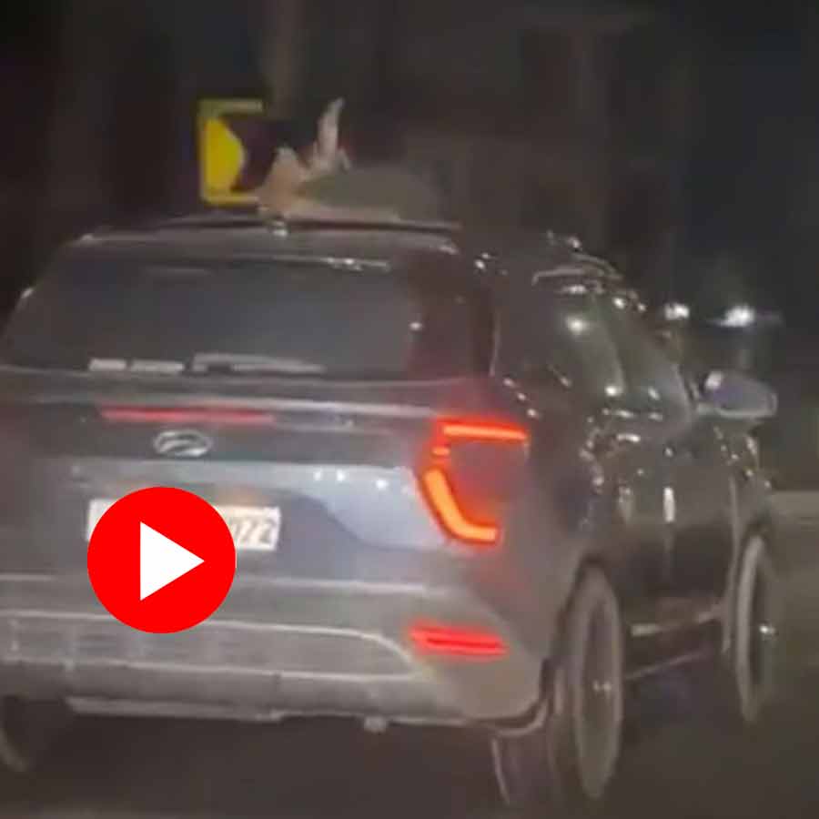 young couple kissing and hugging from sunroof of a moving car