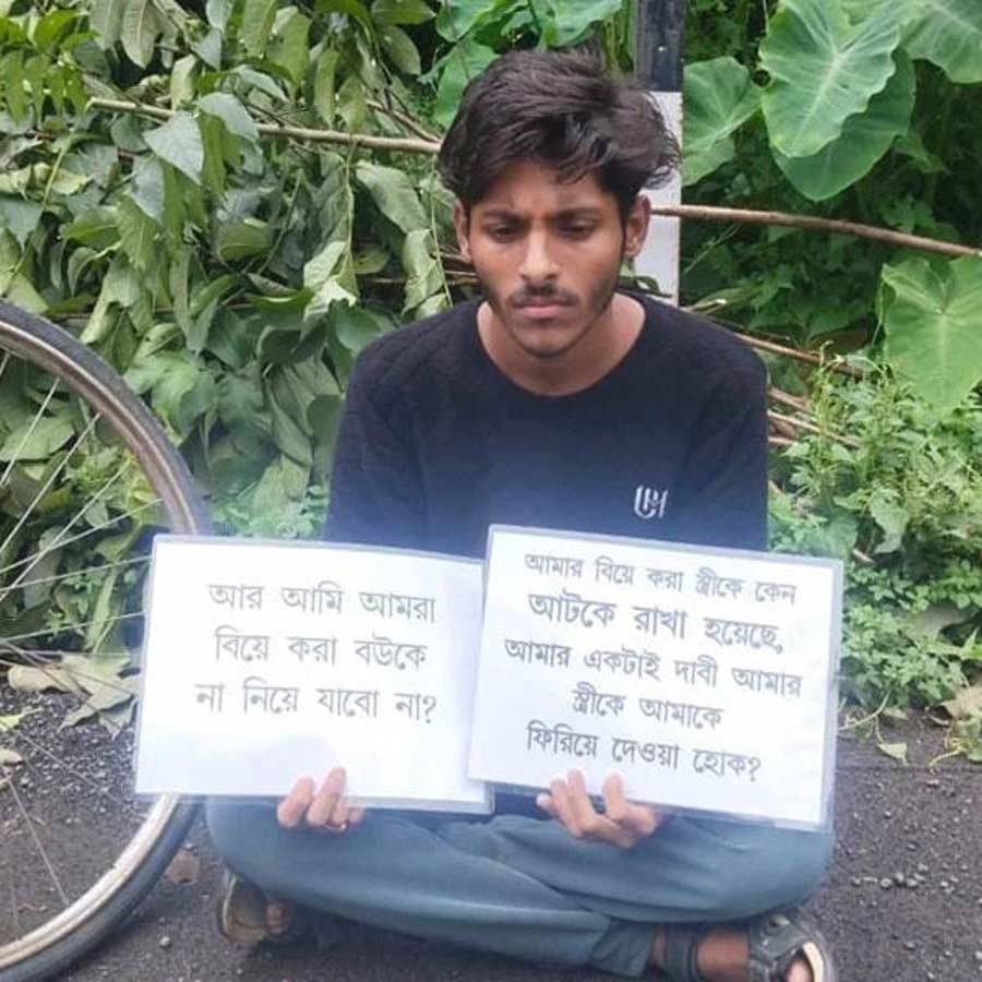 Husband Suman Dhar holds a placard in front of his in-laws' house demanding his wife's return dgtld