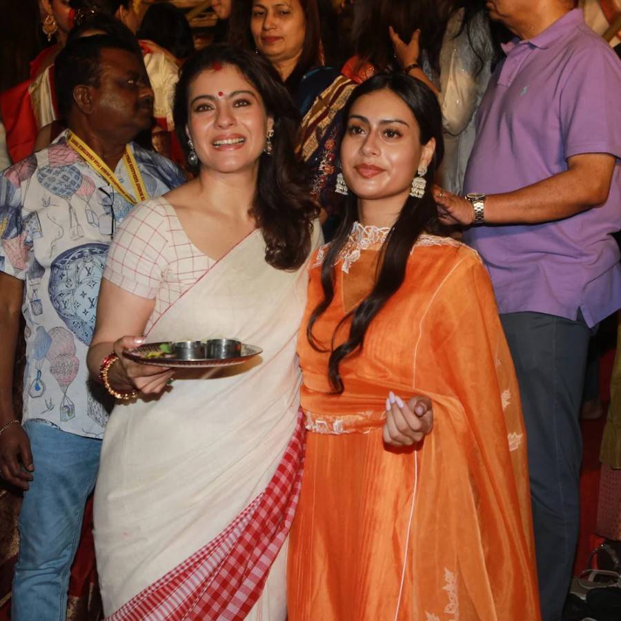 অন্য দিকে নজর কাড়লেন কাজল। একে বারে বাঙালি লুকে, অফ-হোয়াইট তাঁতের শাড়ি আর লাল চুড়িতে যেন পুজো প্যান্ডেলেই ঘর খুঁজে পেলেন। পাশে মেয়ে নিসা, গায়ে গেরুয়া রঙের ঝলমলে আনারকলি।