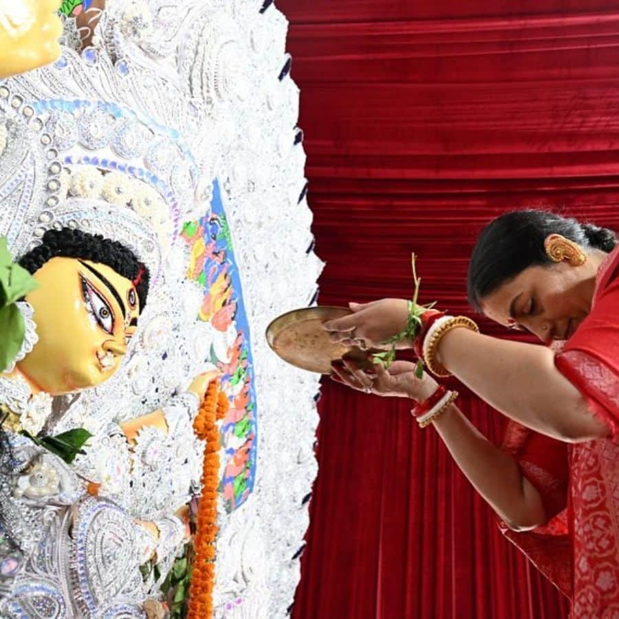 তাঁর পরনে ছিল লাল শাড়ি, হাতে শাঁখা-পলা। সাবেকি সোনার গয়না আর ভক্তিপূর্ণ নমস্কারের ভঙ্গিমা — পুজোর প্রতি তাঁর নিষ্ঠা ছিল চোখে পড়ার মতো।