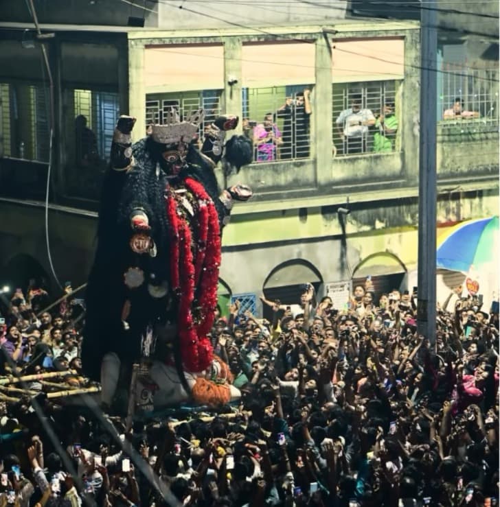 একটি বাঁশের মাচায় করে দেবীর মূর্তি কাঁধে নিয়ে বয়ে চলেন ভক্তরা। পিছনে পিছনে আরও অগুন্তি ভক্তের সারি। সুবিশাল প্রতিমাকে নিয়ে কাঁধে বাঁশ থাকা অবস্থাতেই লাফিয়ে লাফিয়ে নাচের ভঙ্গি করেন ভক্তরা। দেখে মনে হয়, তাঁদের নেচে উঠছেন স্বয়ং দেবীও।    