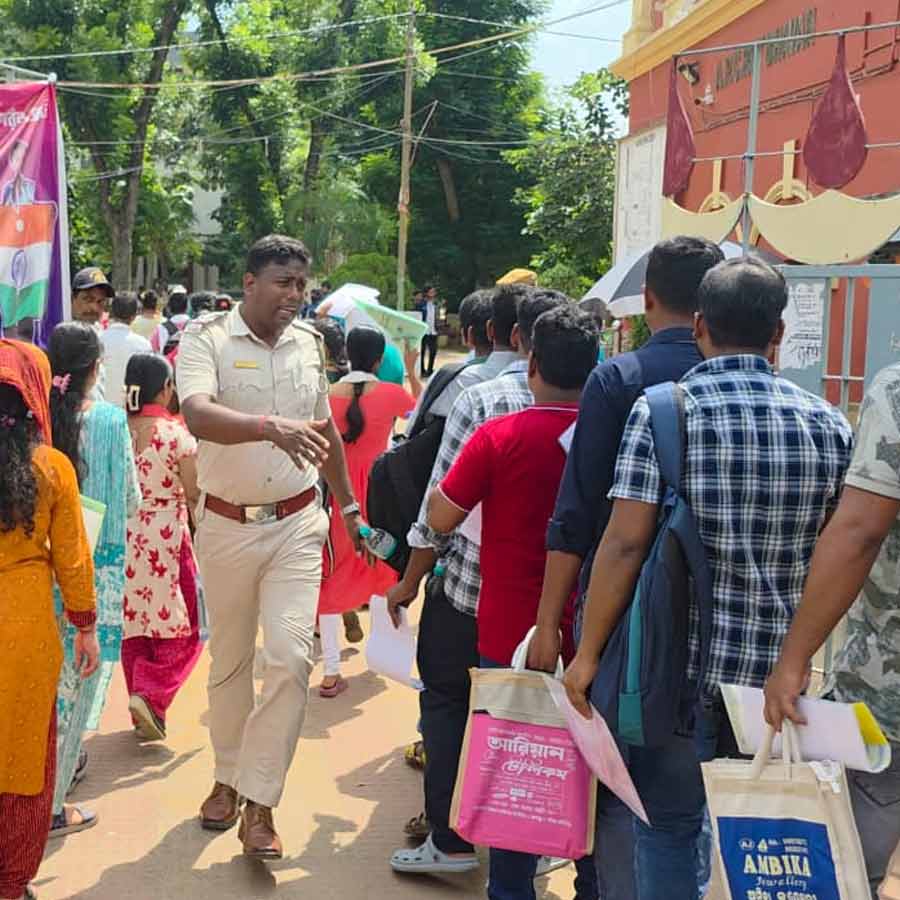 পরীক্ষাকেন্দ্রে ঢোকার আগে পরীক্ষার্থীদের লাইন সামলাচ্ছেন এক পুলিশকর্মী। পশ্চিম মেদিনীপুরের একটি পরীক্ষাকেন্দ্রে।