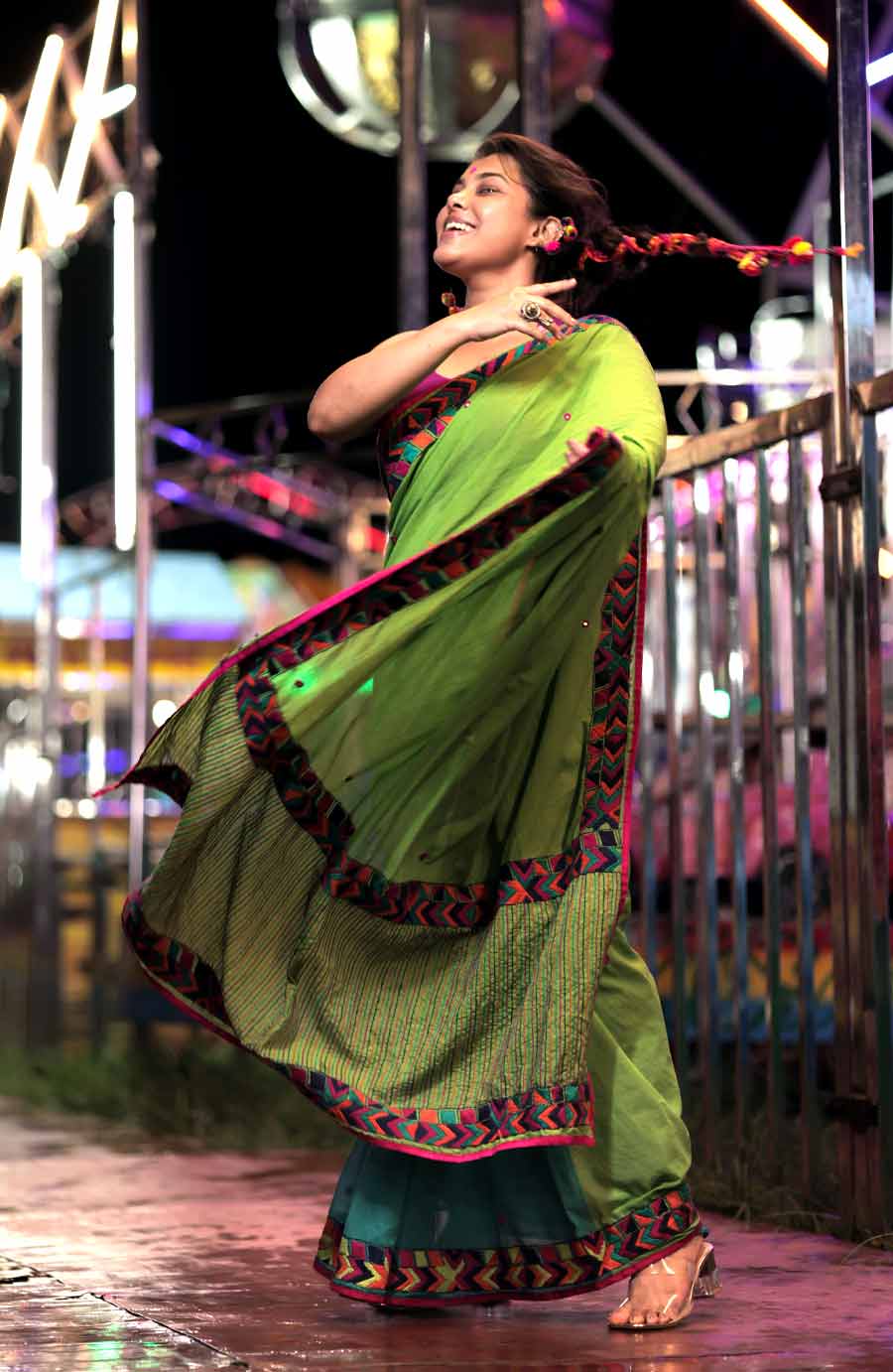 পুজো মানে মেলাও। মানুষের মেলা। মিলনোৎসব বা বলা ভাল পুনর্মিলনোৎসব। সারা বছর দেখা করতে না পারা স্বজন-বন্ধুদের পুনর্মিলন। কারণ, মেলার নাগরদোলার মতোই জীবনও আকাশপাতাল ঘুরিয়ে শেষমেশ নামিয়ে দেয় মাটিতেই। উৎসবের শাড়িতে মডেল শ্রমণাও তাই হাজির মেলার মাঠে। পিছনে নাগরদোলা। শাড়ির জমিতে সবুজের ডাক। পাড়ে খুশির রঙিন সুতোয় বোনা জ্যামিতিক নকশা। আর জমি জুড়ে ছোট ছোট আয়নার বুটিতে পুজোর আলোর ঝিকিমিকির প্রতিফলন।