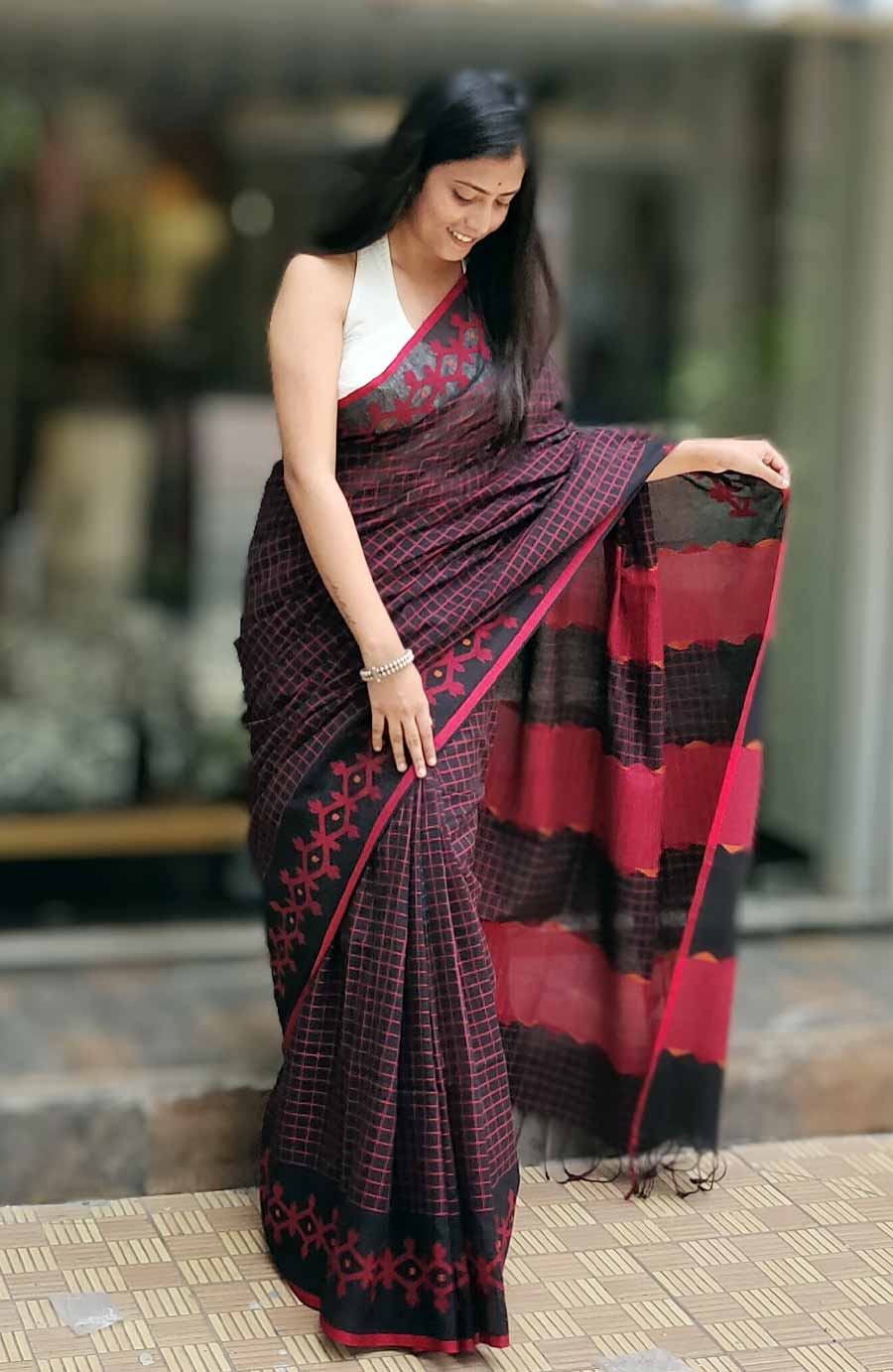 অরণ্য-এর এই শাড়িতেও রয়েছে চেক নকশা। কালো জমিতে সরু লাল সুতোর ছোট ছোট চেক। পাড়ে জামদানি করাত কাজের জ্যামিতিক নকশা। লাল-কালোর বৈপরীত্য চিরকালই পছন্দ শিল্পীদের। কারণ, এই রং শক্তির প্রতীক, এই রংমিলন্তিতে চোখ বন্ধ করে ভরসা করা যায়। কিছু না হলে লাল কালো থাকলে সাজ ভাল হবেই— জানেন সকলে। পুজোর শাড়িতে তাই সেই চিরকালীন রঙের বৈপরীত্যে ভরসা রেখেছে অরণ্যও। 
