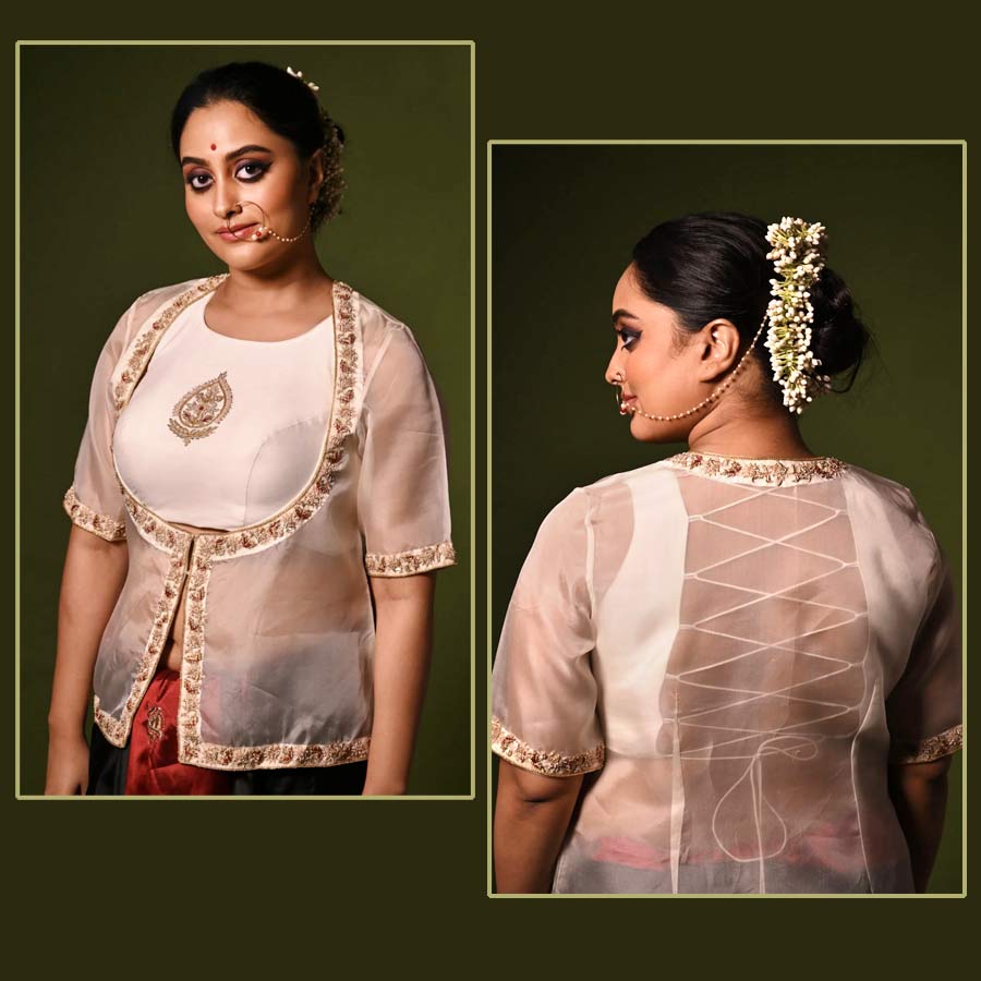 আড়াল করলেও আড়াল হল কই? সাদা পিঠখোলা ব্লাউ়জ়ে ক্রিসক্রস স্টাইলে দড়ি বাঁধা, তার উপর অরগ্যানজ়ার জ্যাকেট। পুজোয় সবার চেয়ে আলাদা সাজতে চাইলে ‘পরমা’র এমন ‘মুমতাজ় জ্যাকেট ব্লাউজ়’ পরে নিলেই হল। জ্যাকেটের ধার বরাবর জারদৌসি ফুলেল কারুকাজ আরও আকর্ষণীয় করে তুলেছে ব্লাউজ়টিকে। পুজোয় সাবেকি কায়দায় সাজগোজ করতে চাইলে এমন একটি ব্লাউজ় কিন্তু সাজে আলদা মাত্রা যোগ করতে পারে। শাড়ির সঙ্গে জ্যাকেট ব্লাউজ়— এ বার পুজোয় এমন মেলবন্ধনে আপনার সাজ হতে পারে একেবারে চোখ ধাঁধানো। 