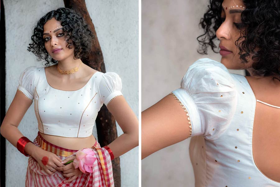 এ বছর ব্লাউজ়ের ফ্যাশনে ঘটি হাতার বেশ রমরমা। সাদা ব্লাউজ়ের সঙ্গে যে কোনও রঙের শাড়ি বেশ ভাল মানায়। দুধ সাদা কাপড়ের উপর সোনালি চুমকি আর লেসের কারুকাজ ঘটি হাতা ব্লাউজ়টির সাজে বেশ চমক এনেছে। খুব বেশি চকমকে সাজগোজ যাঁদের পছন্দ নয়, তাঁদের পছন্দের তালিকায় থাকতেই পারে এমন একটি ঘটি হাতা ‘কানাই’ ব্লাউজ়। ‘সুতা’র পুজো সম্ভারেও পেয়ে যাবেন এমন ব্লাউজ়ের নানা নকশা। ছিমছাম হলেও আপনার সকালবেলার পুজো লুকের সঙ্গে এমন ব্লাউজ় কিন্তু বেশ মানাবে। 