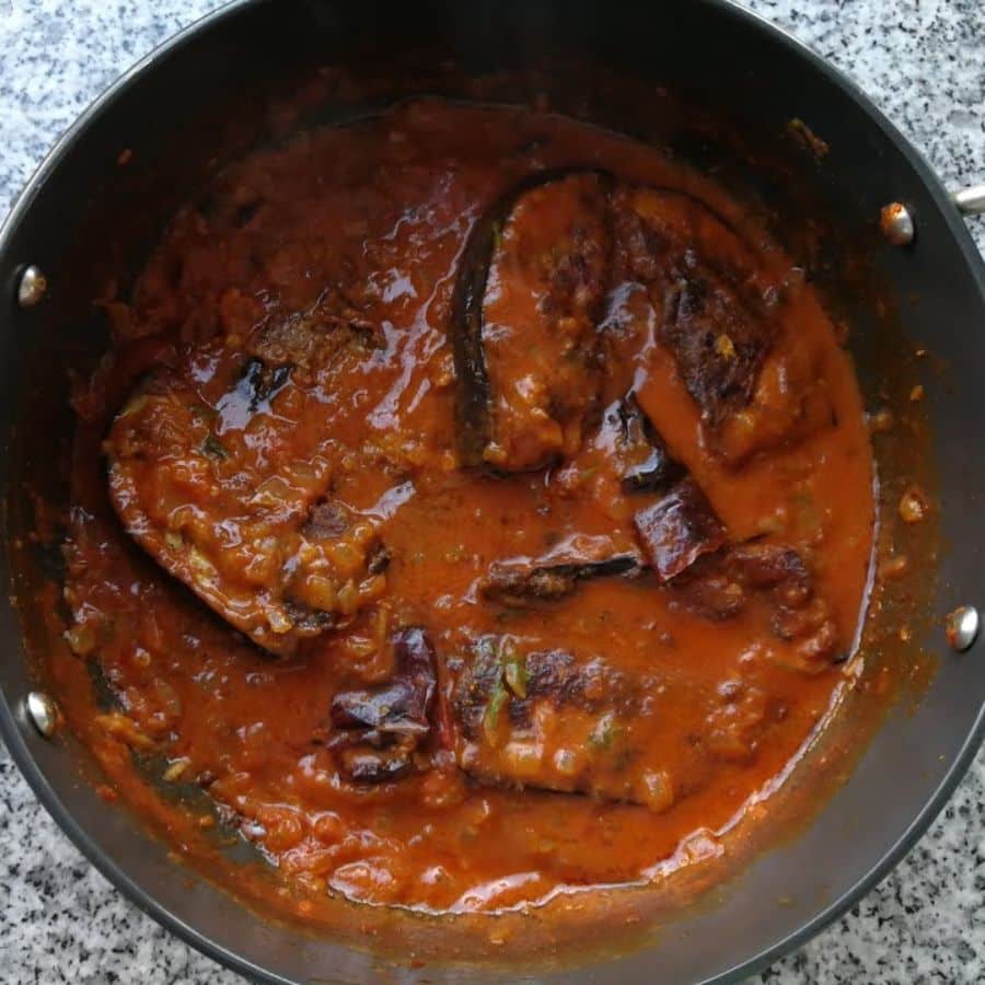 ৮.  কড়ায় ঢাকনা দিয়ে দিন এবং একেবারে কম আঁচে ৫-৭ মিনিট রান্না করুন। বেগুন পুরোপুরি সেদ্ধ হয়ে গেলে এবং গ্রেভি ঘন হয়ে এলে নামিয়ে নিন।