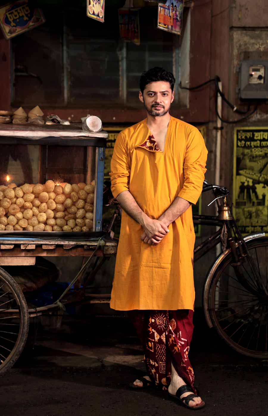 বাংলার আদি-অকৃত্রিম মোম বাটিক। শান্তিনিকেতনে এই মোম বাটিকের কাজ বিখ্যাত। তবে বাটিকের চল রয়েছে ভারতের অন্য প্রান্তেও। ছবিতে মডেল যে পাঞ্জাবিটি পরেছেন, সেটির গলা বেনিয়ানের আদলে। বোতাম খুলে আলগা ভাঁজ হয়ে পড়েছে একটি প্রান্ত। তেমনটা যে হতে পারে জানাই ছিল। তাই ভিতরেও বাটিকের নকশার অ্যাপ্লিক করা হয়েছে। যে নকশা রয়েছে সঙ্গের গাঢ় চকোলেট ধুতির পাড়ে। 