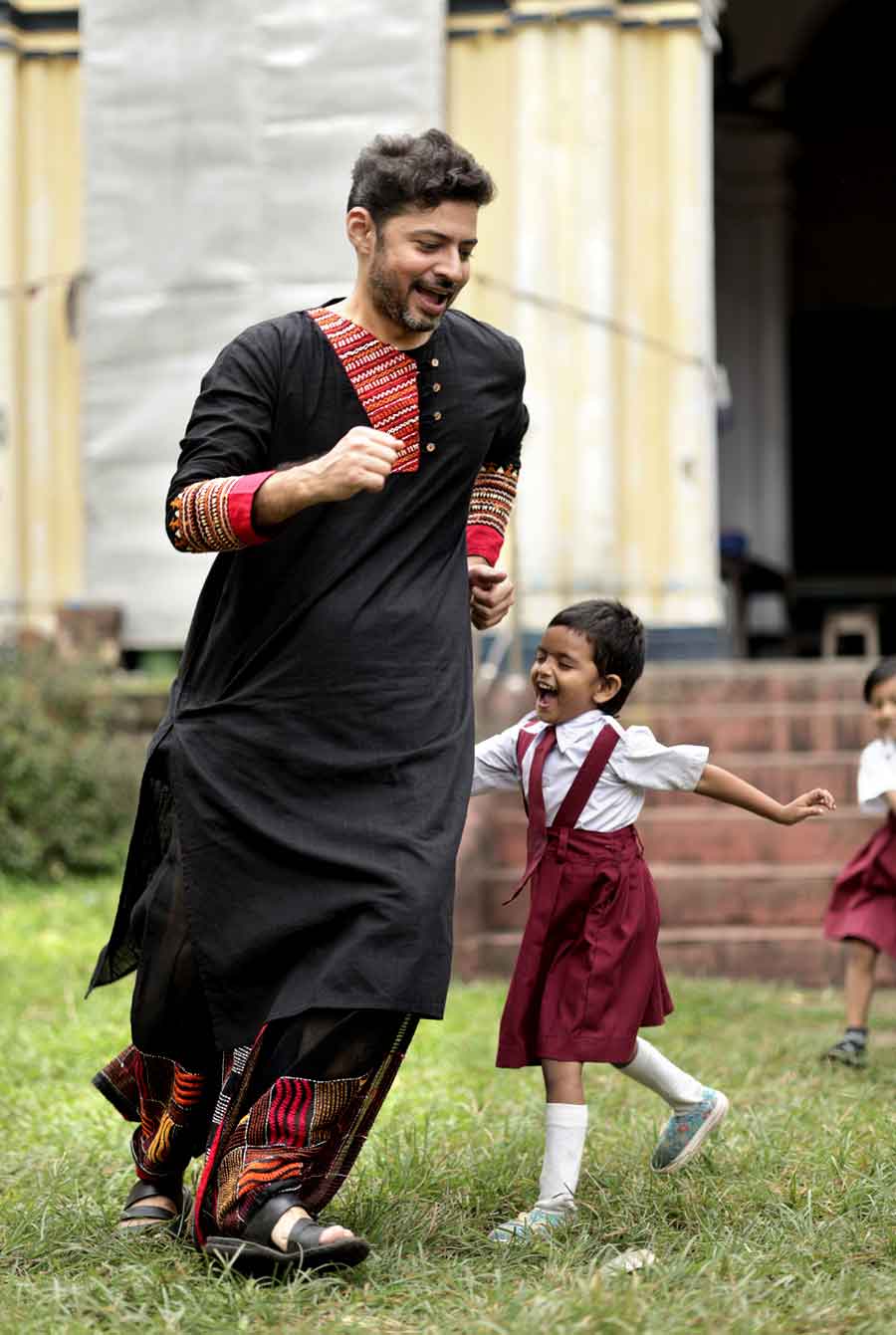 কালো খাদি কটনের পাঞ্জাবির উপর রঙিন সুতোর প্যাচওয়ার্ক। গলায় অ্যাসিমেট্রিক নকশা, হাতে চওড়া কাজ। পাঞ্জাবির সঙ্গে মিলিয়ে কালো ধুতিতেও লাল-হলুদ-কমলা সুতোর ঠাসা কাঁথার কাজ। পুজোর সকালে কোনও ঠাকুর দালানে সময় কাটাতে হলে এমন একটি ধুতি-পাঞ্জাবি যেমন আরাম দেবে, তেমন মানিয়ে যাবে পরিবেশের সঙ্গেও। 
