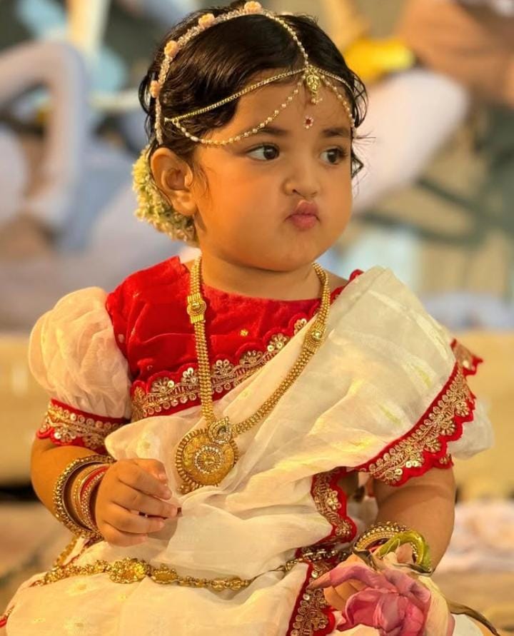 লাল-সাদা শাড়িতে খুদে কন্যা। মানানসই ব্লাউজ, হাতে চুড়ি, কানে দুল। এই দুই রঙের মিশেল যেন পুজোয় বাঙালির চিরন্তনী সাজ। 