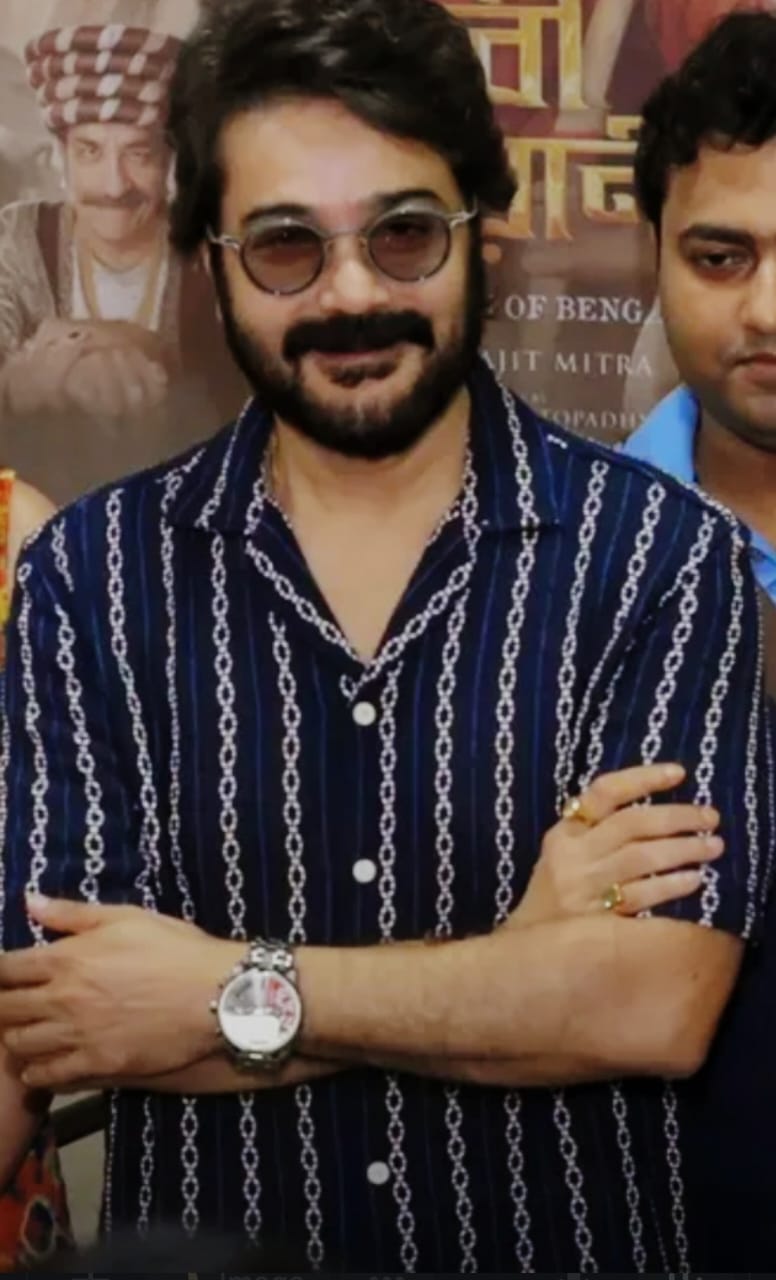 আবার কখনও হালকা রঙের চেন-স্ট্রাইপ প্রিন্টের গাঢ় নীল শার্টে তিনি একেবারে ক্যাজ়ুয়াল আড্ডার মেজাজে। কবজিতে ঘড়ি আর হাতে আংটি—এই লুকে আরাম আর ফ্যাশন মিলেমিশে একাকার।