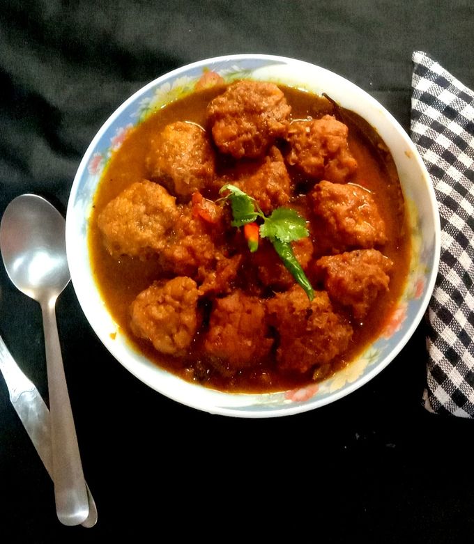 এ বার অন্য একটি কড়ায় আর একটু তেল দিয়ে তেজপাতা, গোটা জিরে, শুকনো লঙ্কা ও গোটা গরম মশলা (এলাচ, দারচিনি, লবঙ্গ) ফোড়ন দিন। সুগন্ধ বার হওয়া পর্যন্ত অপেক্ষা করুন। ফোড়ন দেওয়ার পরে পেঁয়াজ বাটা ও আদা-রসুন বাটা দিয়ে কষান। এরপর টোম্যাটো বাটা বা পিউরি, হলুদ, লঙ্কা গুঁড়ো, জিরে ও ধনে গুঁড়ো এবং পরিমাণ মতো নুন ও চিনি যোগ করুন। মশলা থেকে তেল ছেড়ে আসা পর্যন্ত কষাতে থাকুন।