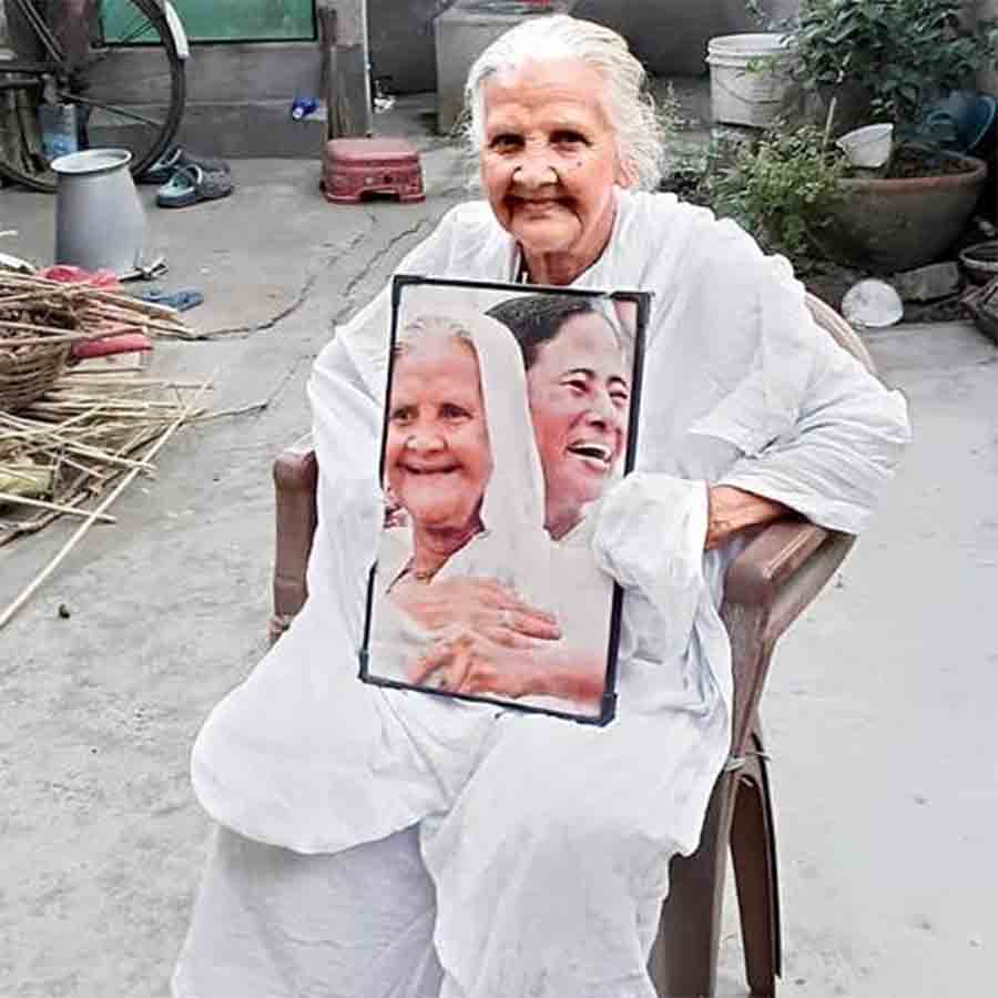 ঘরের দাওয়ায় মুখ্যমন্ত্রীর সঙ্গে নিজের ছবি হাতে বসে সরস্বতী দাস।