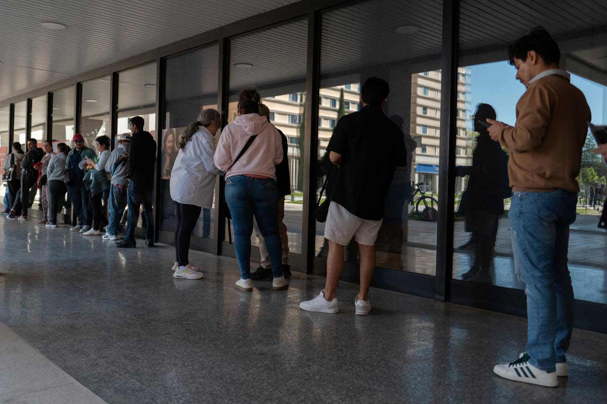 চিন্তিত: স্পেনে কত দিন আছেন, সেই সংক্রান্ত নথি জোগাড়ের লাইনে অভিবাসীরা।