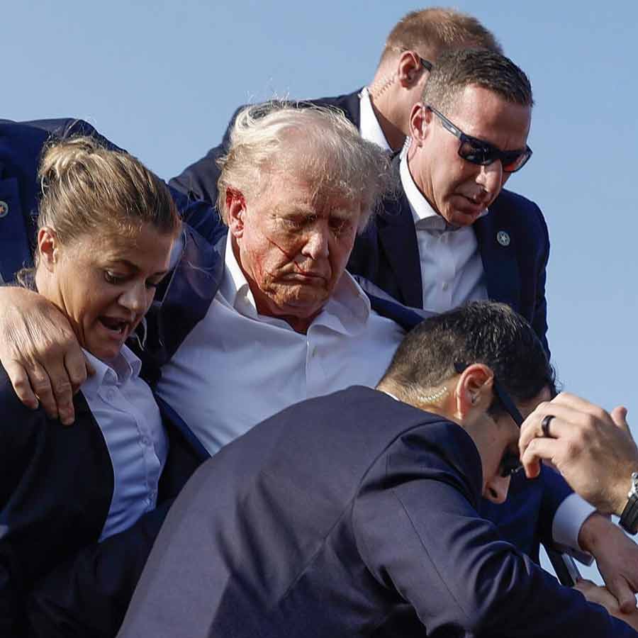 ২০২৪ সালের ১৩ জুলাই পেনসিলভেনিয়ায় কান ঘেঁষে গুলি বেরিয়ে যাওয়ার পর মঞ্চ থেকে নামিয়ে আনা হচ্ছে ডোনাল্ড ট্রাম্পকে।