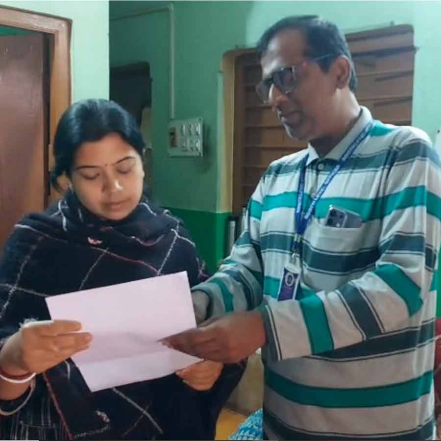 (বাঁ দিকে) স্ত্রী সুস্মিতা মজুমদারের হাতে নোটিস তুলে দিচ্ছেন বিএলও রাজশেখর মজুমদার (ডান দিকে)।