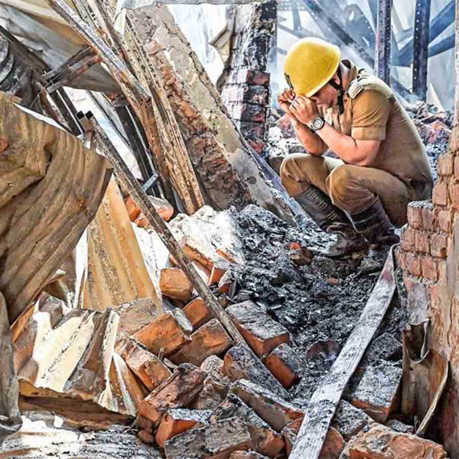 বিশ্রাম: নাজিরাবাদের পোড়া গুদামে একনাগাড়ে কাজ করতে করতে একটু জিরিয়ে নিচ্ছেন এক দমকলকর্মী। মঙ্গলবার।