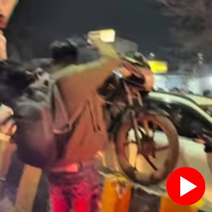 men lifting motorcycles over a traffic divider