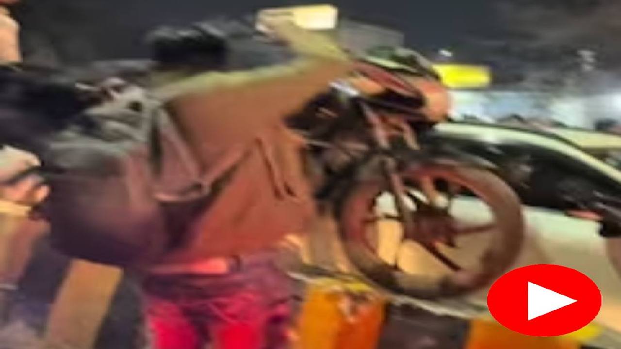 men lifting motorcycles over a traffic divider