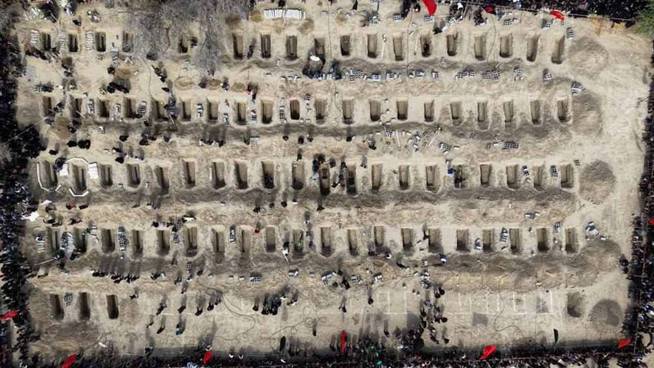 ইরানের স্কুলে আমেরিকা-ইজ়রায়েলের হামলায় মৃত পড়ুয়াদের গণকবর। ছবি: রয়টার্স।