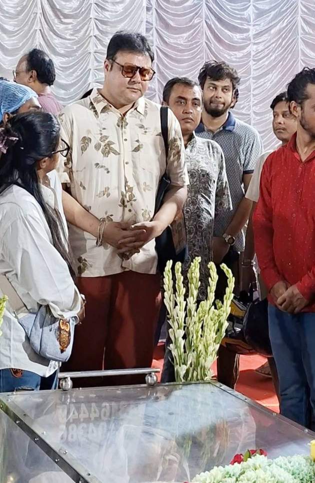 শোকস্তব্ধ সুজয়প্রসাদ চট্টোপাধ্যায়। রঙিন চশমায় চোখ ঢেকেছিল তাঁর ভেজা চোখ। সুজয় পরিচালককে শ্রদ্ধা জানিয়ে তাঁর পায়ে ফুলের তোড়া সাজিয়ে দেন।