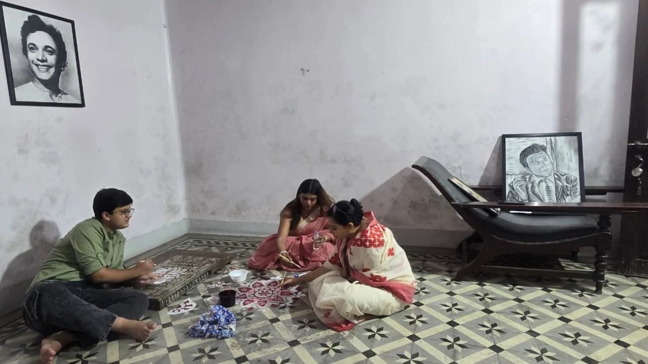 আলপনা দিতে ব্যস্ত পরিবারের সদস্যরা।