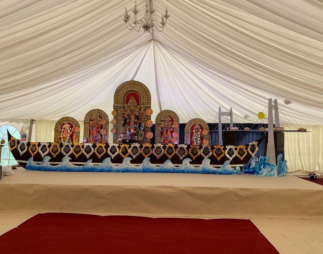 লন্ডনের পশ্চিমে বার্কশায়ার কাউন্টির স্লাও শহরে বাঙালিরা এক সঙ্গে মিলে গড়ে তুলেছে তাদের পুজোর ক্লাব ‘আড্ডা’। এই প্রথম দুর্গাপুজো হচ্ছে সেখানে।প্রতিমা এসেছে শেফিল্ড থেকে। প্রতিমা বসানো হয়েছে নৌকোর উপর। কলকাতার দ্বিতীয় হুগলি সেতুর একটি রেপ্লিকাও রাখা হয়েছে তার পাশে।