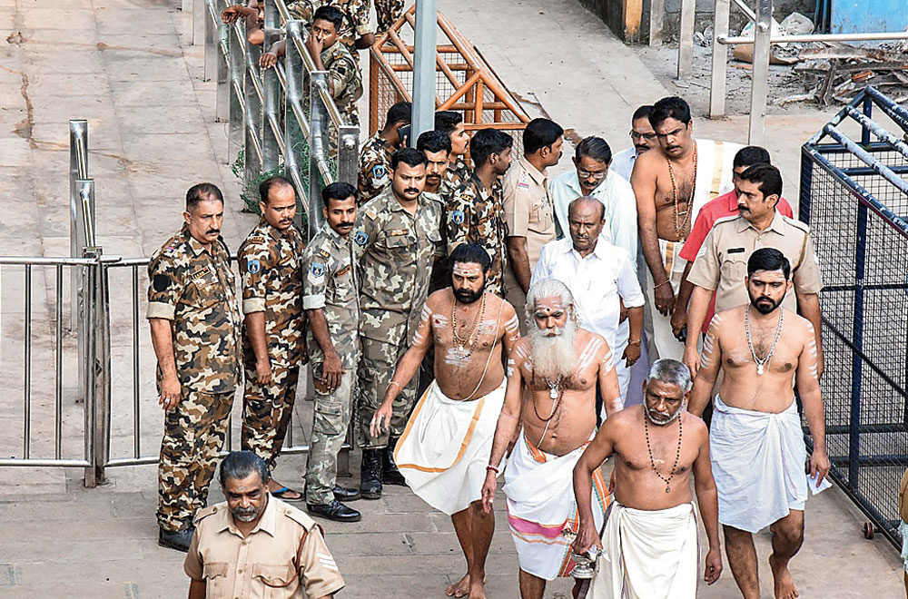 Security personnel stand guard as temple priests walk towards the Sabarimala temple on Monday.