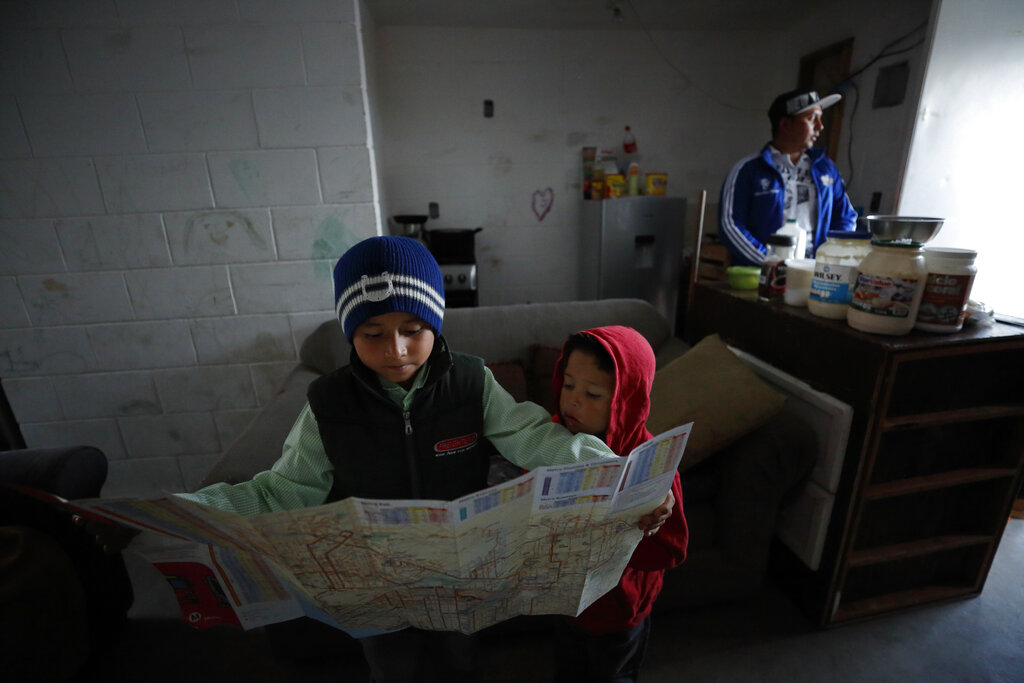 Nahum Perla, left, studies a San Diego map with his younger brother, Carlos Isai Perla, as their father, Juan Carlos Perla, right, gets ready to make the journey from their home on the outskirts of Tijuana, Mexico, to San Diego for an asylum hearing