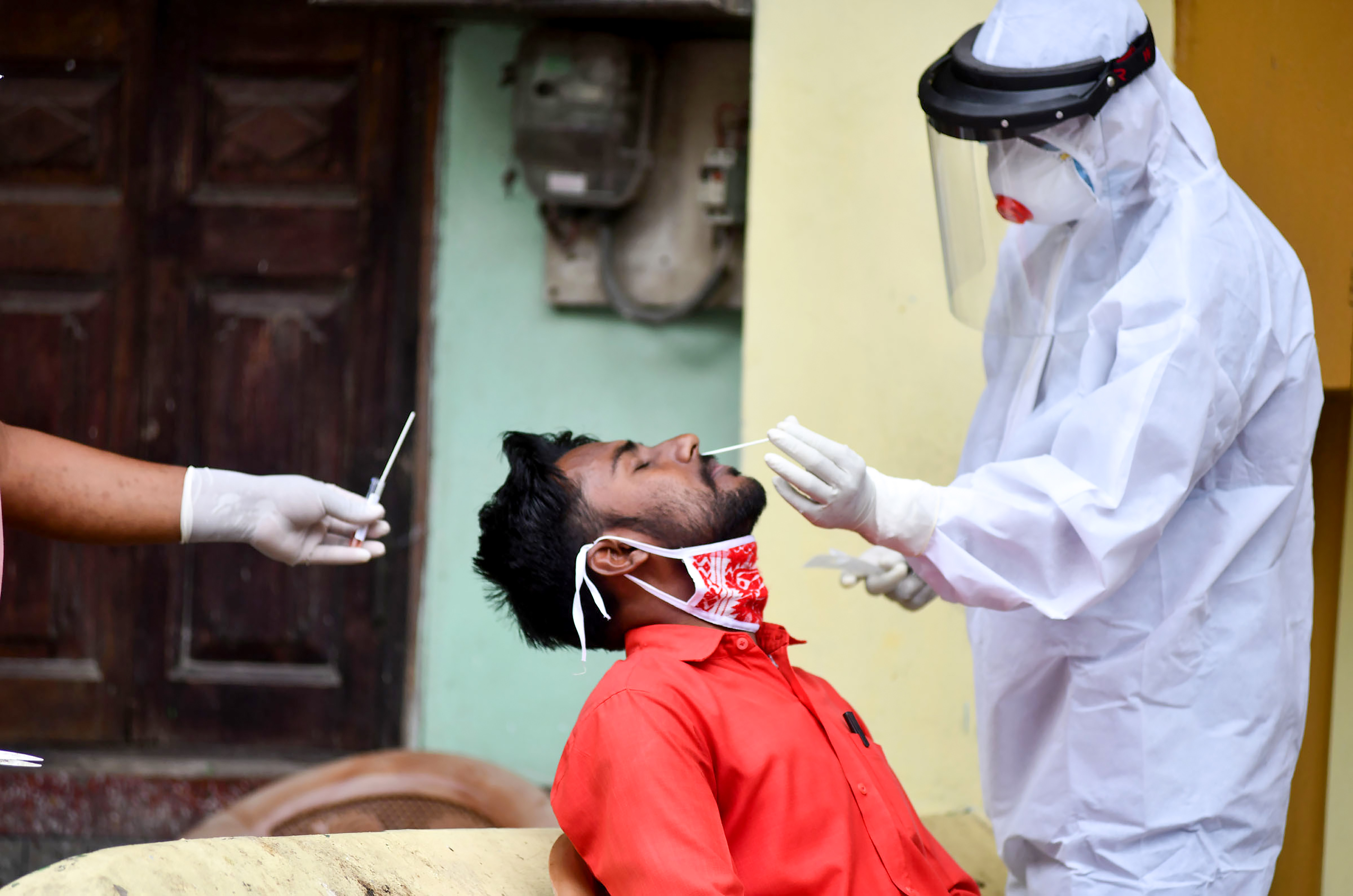 A health worker collects swab sample of a resident for Covid-19 test at a containment zone, during the ongoing nationwide lockdown, in Guwahati, Monday, May 18, 2020.

