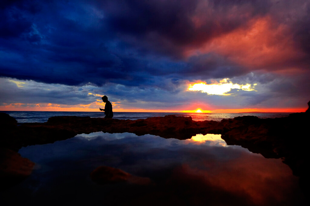 A boy takes pictures by the sea during sunset at Ayia Napa in eastern Cyprus on January 1