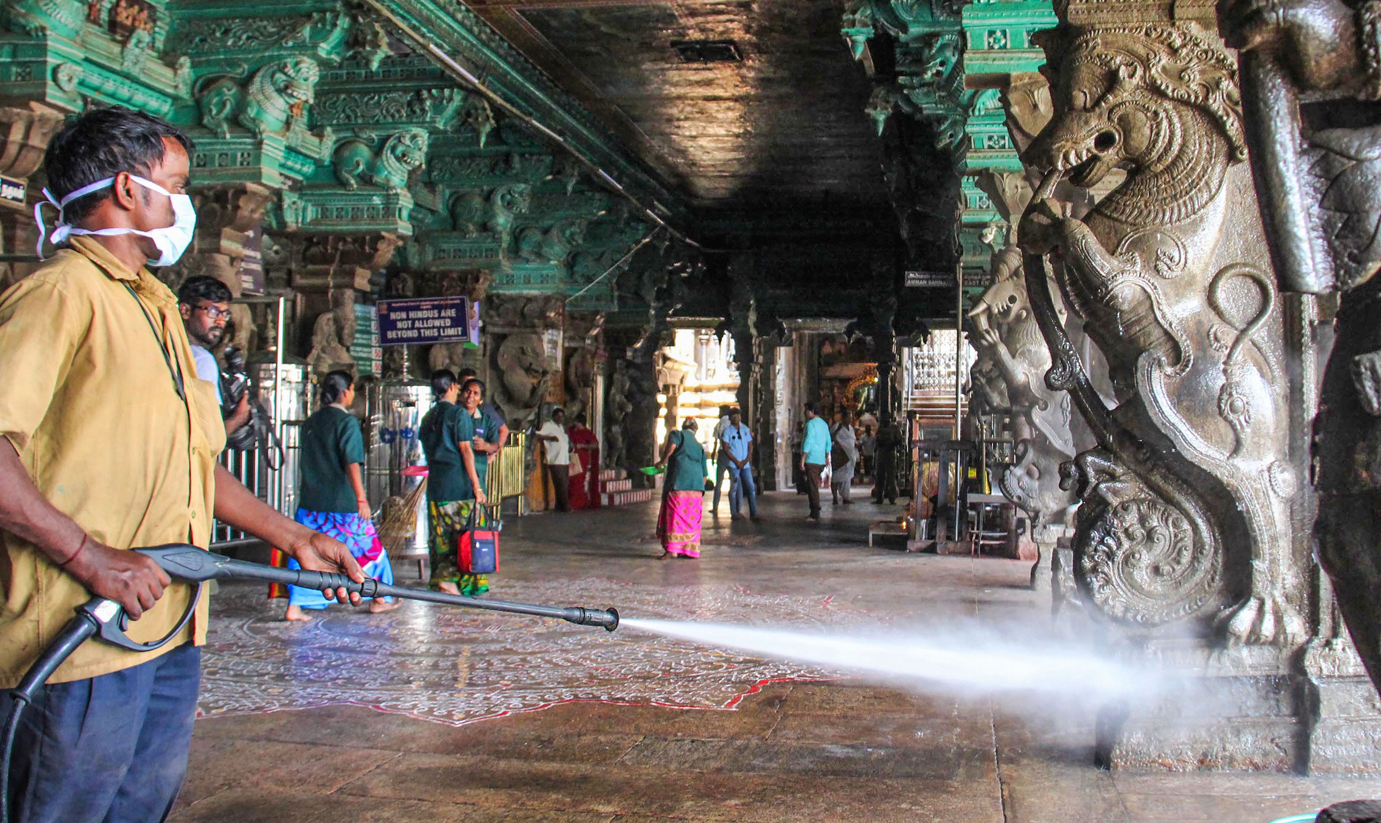 A health official sprays disinfectants in the premises of Meenakshi Amman temple in the wake of coronavirus (COVID -19) pandemic, in Madurai, Monday, March 16, 2020