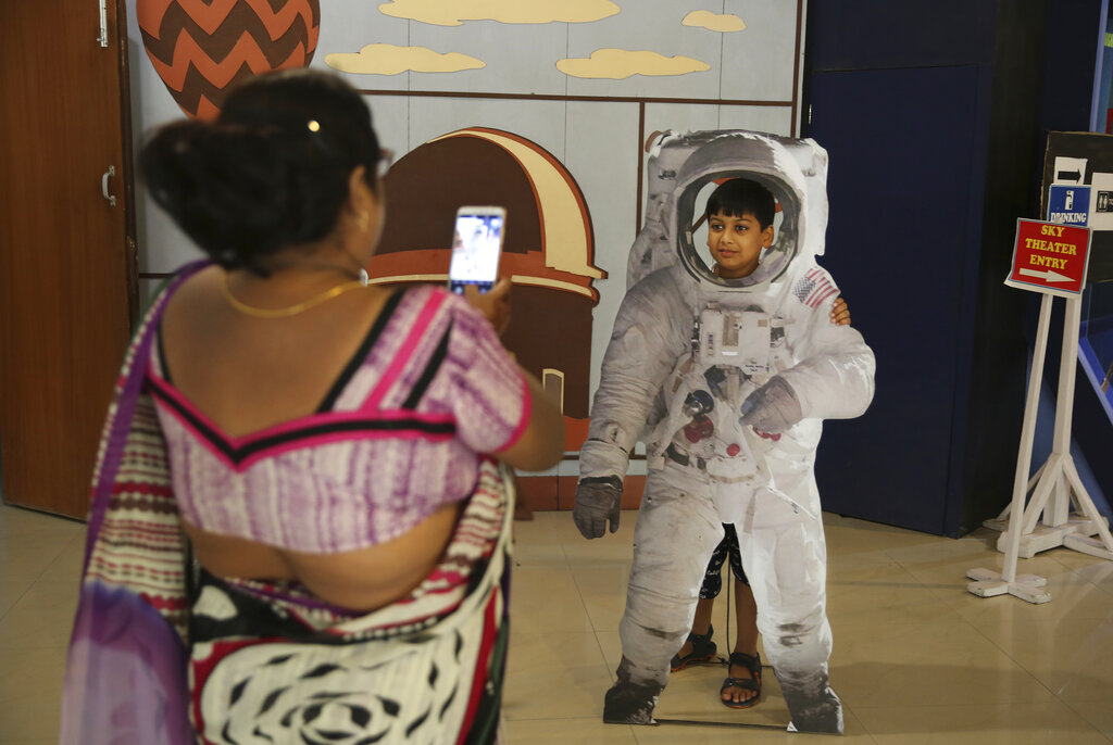 An Indian woman takes a photograph of her son as he poses in a cut-out of an astronaut at the Nehru Planetarium in New Delhi.
