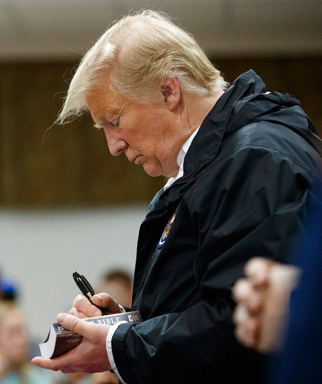 President Donald Trump signs a Bible as he greets people at Providence Baptist Church in Smiths Station, Alabama on Friday, March 8, 2019, during a tour of areas where tornadoes killed 23 people in Lee County, Alabama. 