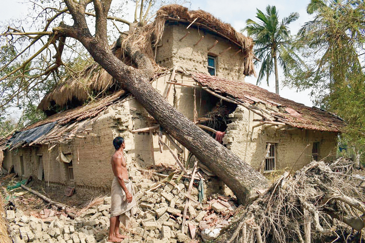 A resident inspects his house damaged by a tree fallen during Cyclone Amphan at Sagar in South 24-Parganas. 