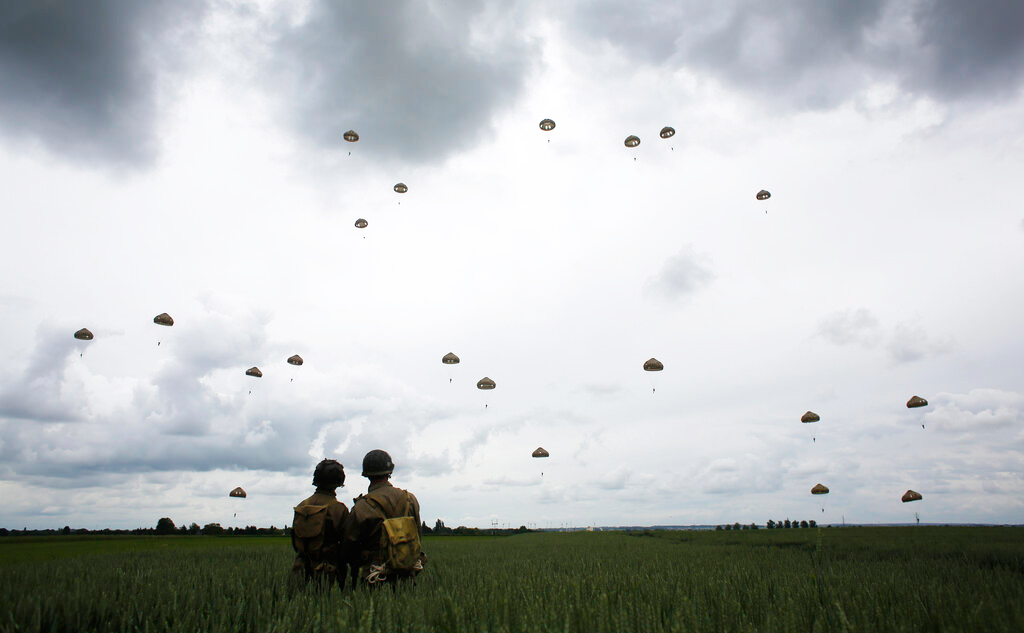 WWII enthusiasts watch French and British parachutists jumping during a commemorative parachute jump over Sannerville, Normandy, on Wednesday, June 5, 2019.