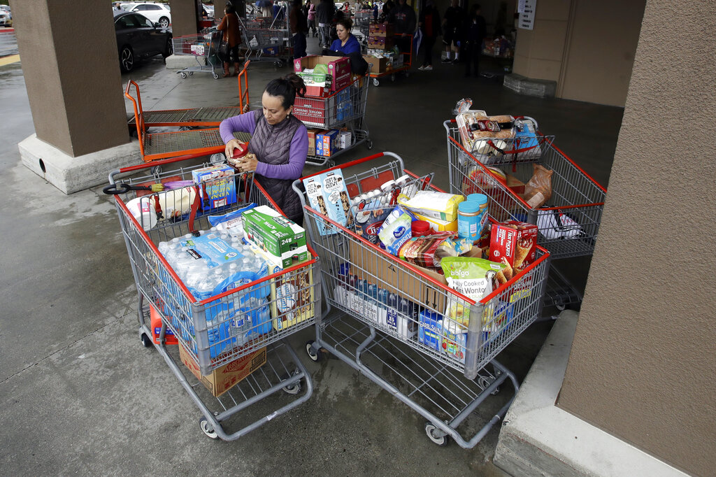 Shoppers exit a Costco warehouse with carts full of goods Saturday, March 14, 2020, in Santa Clarita, Calif.