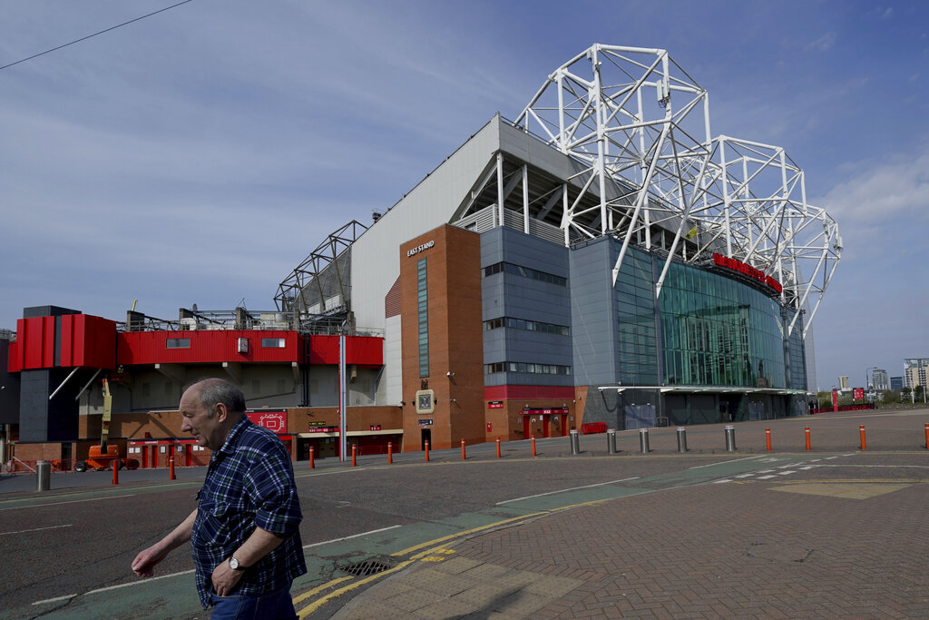 A man walks past the closed Manchester United stadium, Old Trafford, in Manchester, northern England, as the English Premier League football season has been suspended due to coronavirus