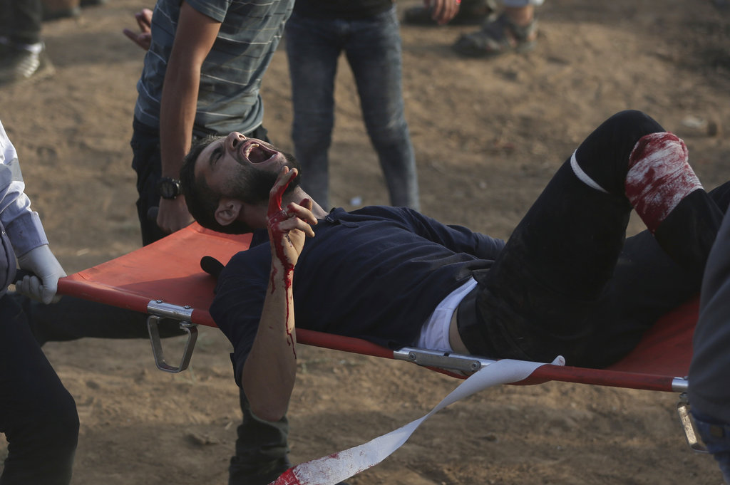 Palestinian medics carry a wounded protester during a protest at the Gaza Strip'