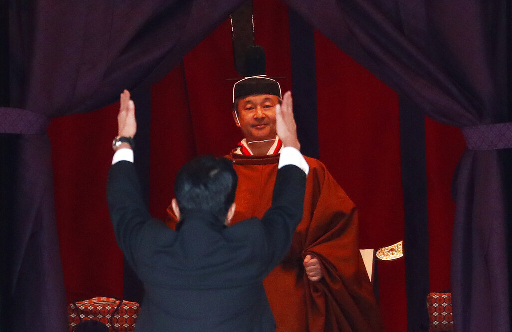 Japan's Prime Minister Shinzo Abe raises his hands as he shouts 