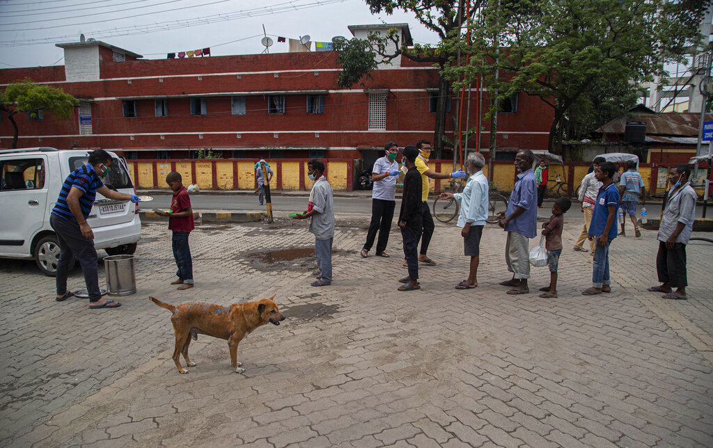 Homeless people stand in queue to receive free food distributed by people during nationwide lockdown in Gauhati, on Thursday, April 23, 2020.
