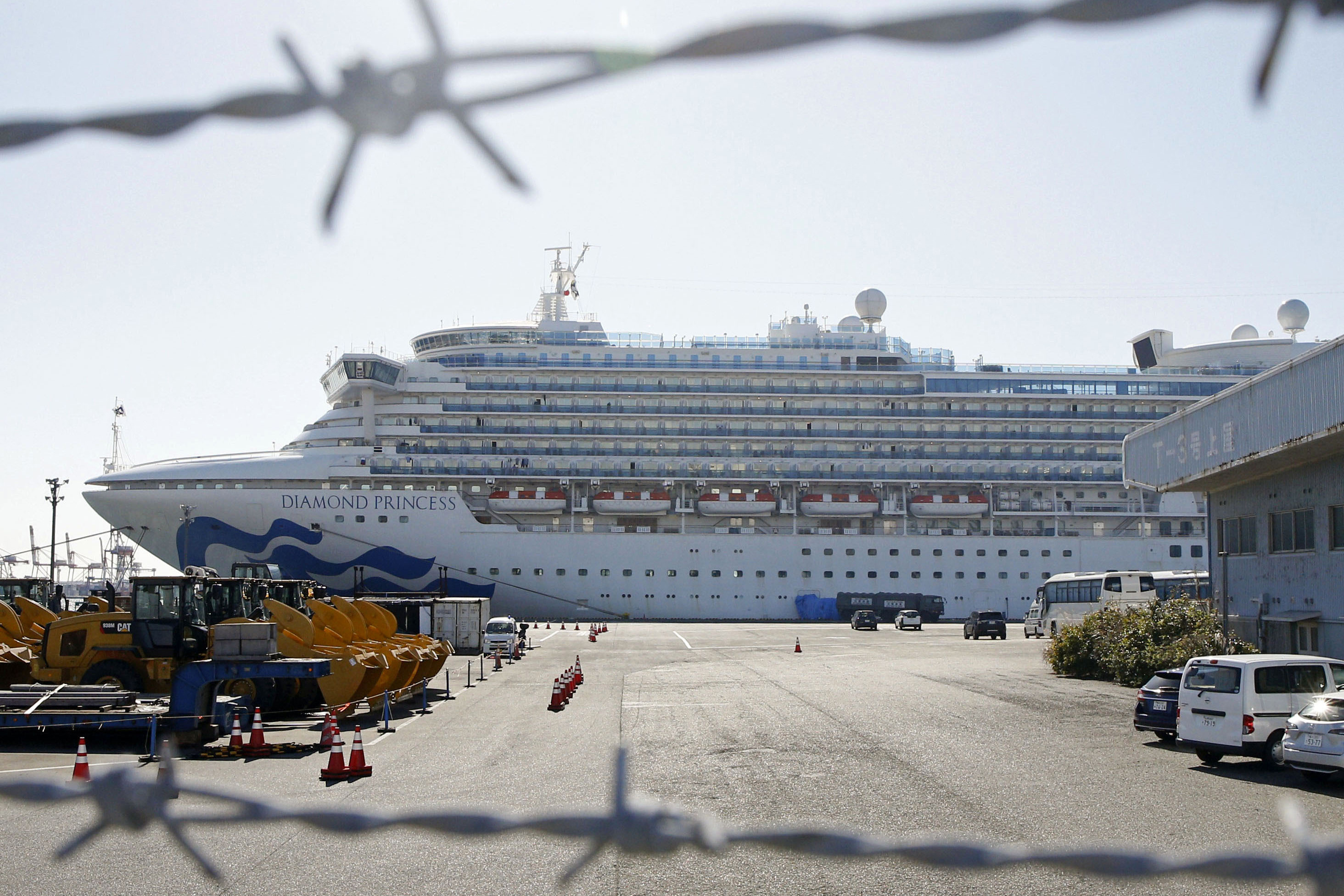 The quarantined ship Diamond Princess is pictured through barbed wire at Yokohama port in Yokohama, near Tokyo on Monday