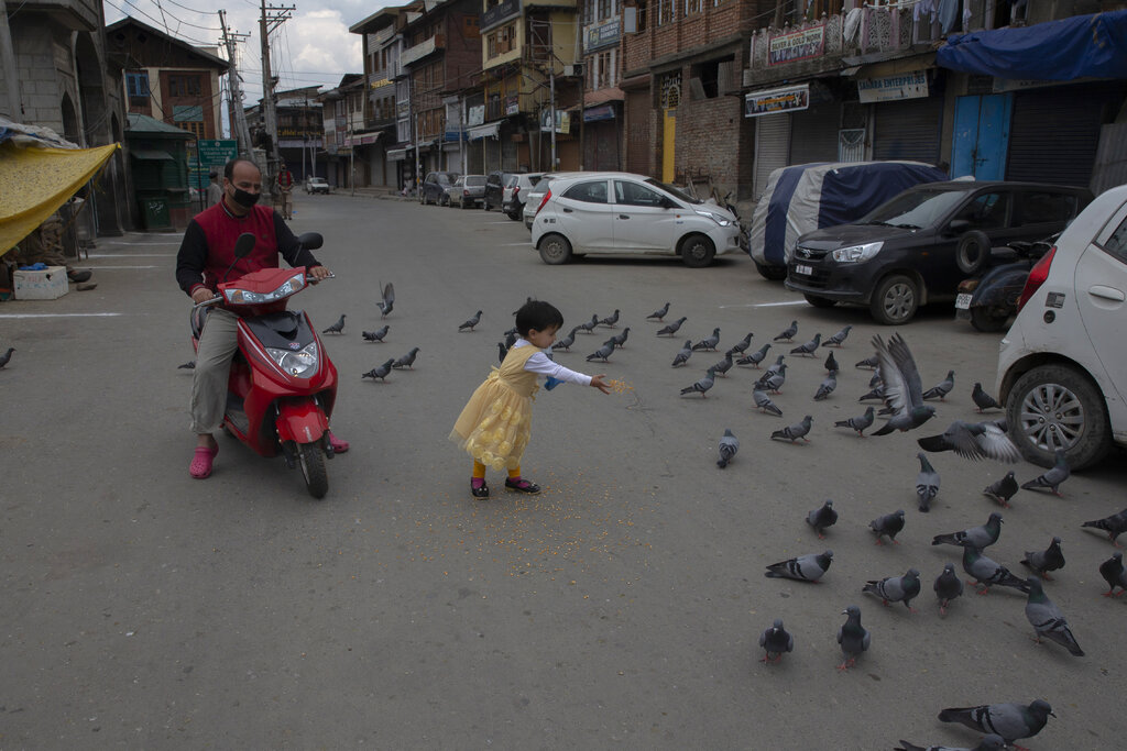 A Kashmiri girl feeds pigeons on a deserted road outside the closed Shah-e-Hamadan shrine on the first day of Ramadan during lockdown to prevent the spread of the new coronavirus in Srinagar, Kashmir, Saturday, April 25, 2020.