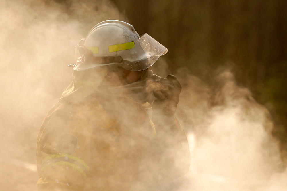 A firefighter covers his face from smoke as he battles a fire near Bendalong, Australia, on January 3