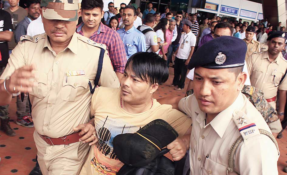 Policemen escort Yogendra Pradhan, leader of the Bimal Gurung faction of the Morcha after their arrival at the Bagdogra airport on Thursday.