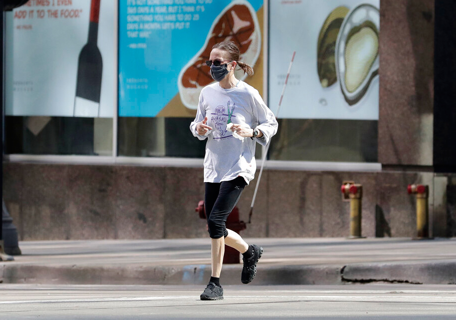 A woman jogs on the street in downtown Chicago, Wednesday, April 8, 2020. No end in sight for the stay-at-home order as Chicagoans fight summer weather temptations. 